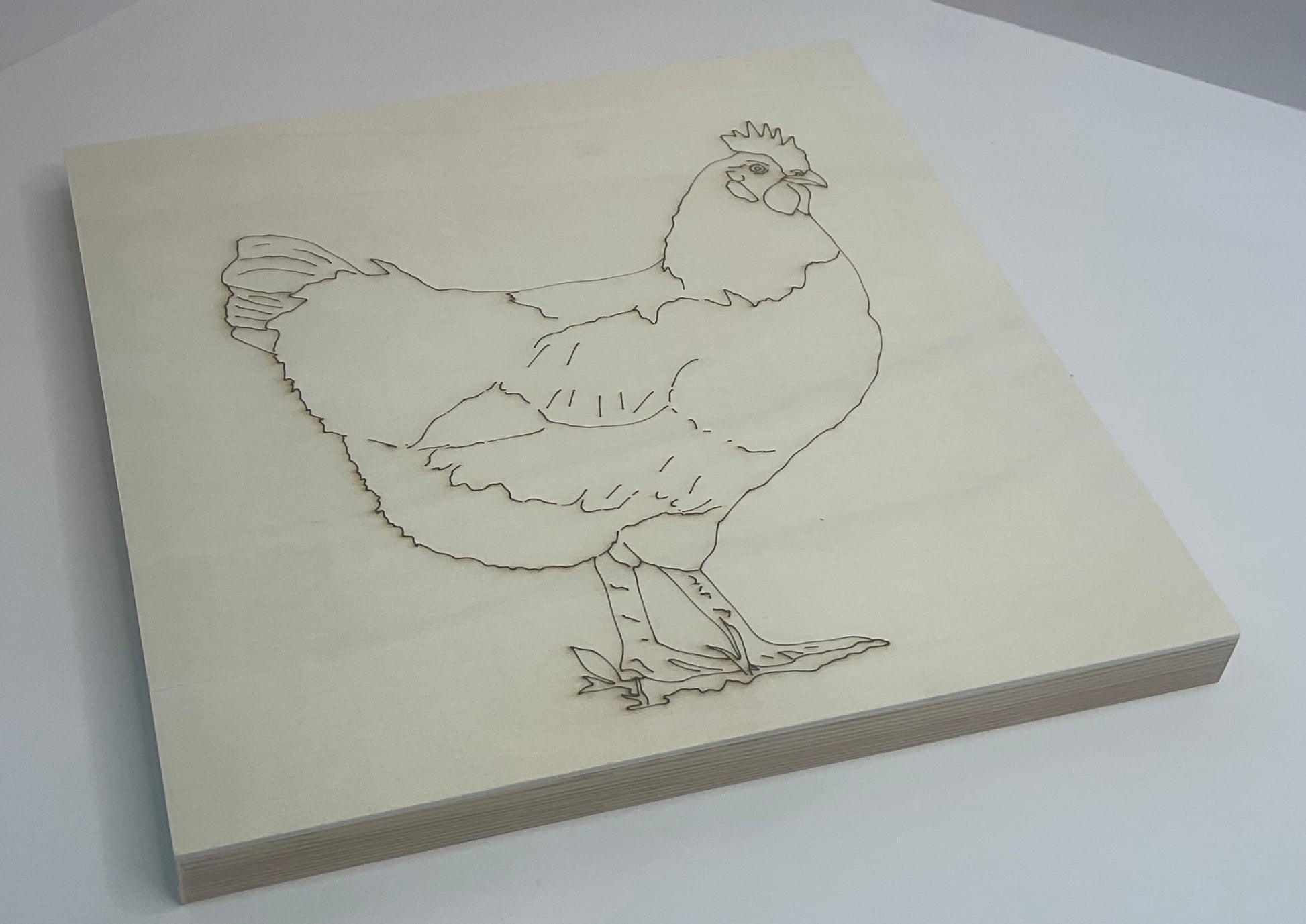 Wooden block with a line drawing of a chicken on a white background